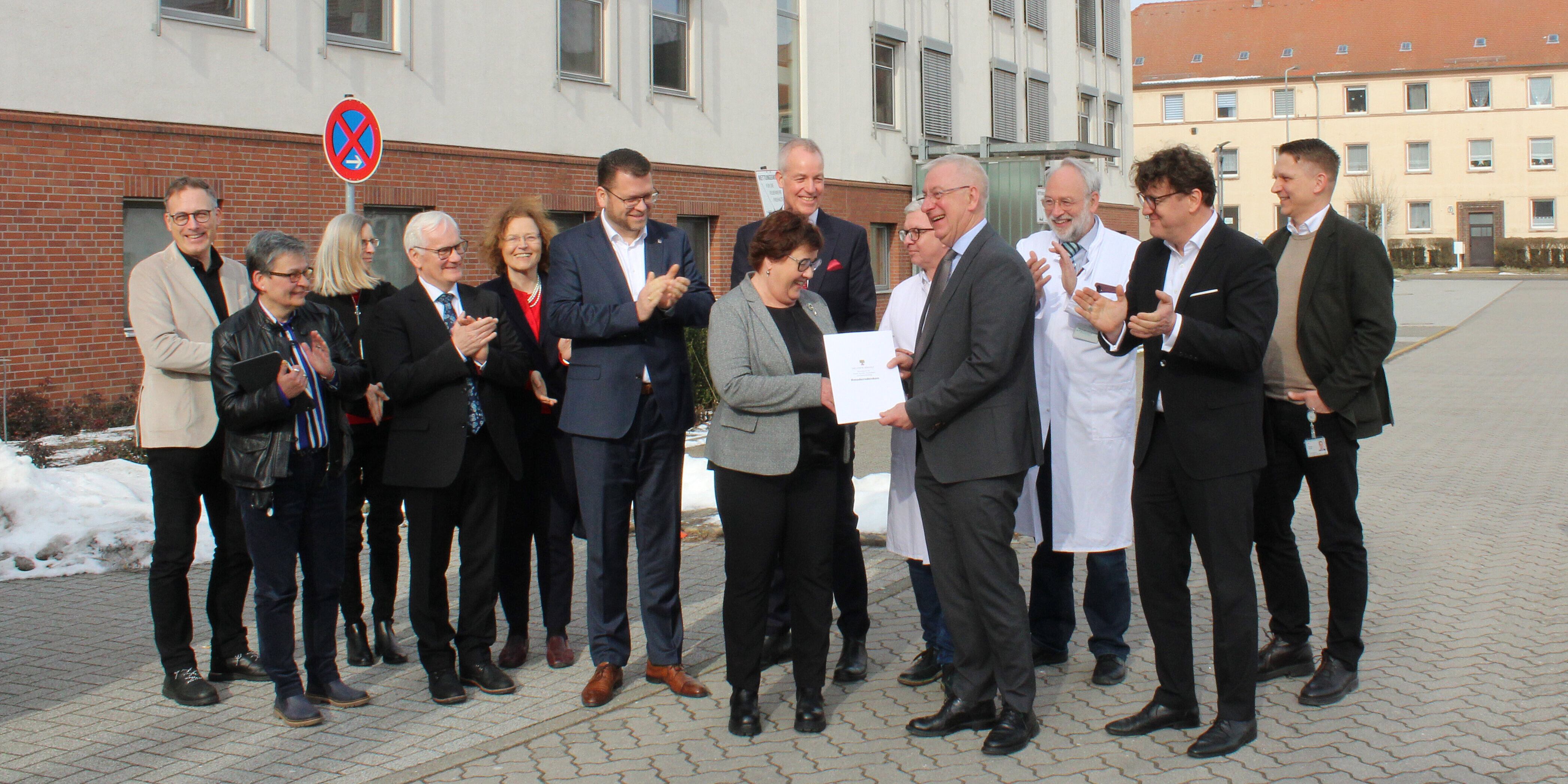 Gesundheitsministerin übergibt 3,52 Millionen Euro zur Umgestaltung der Notaufnahme am Paul Gerhardt Stift in Wittenberg Gruppenbild von Mitarbeitenden des Klinikums, ganz vorne übergibt die Gesundheitsministerin Unterlagen an den Geschäftsführer.