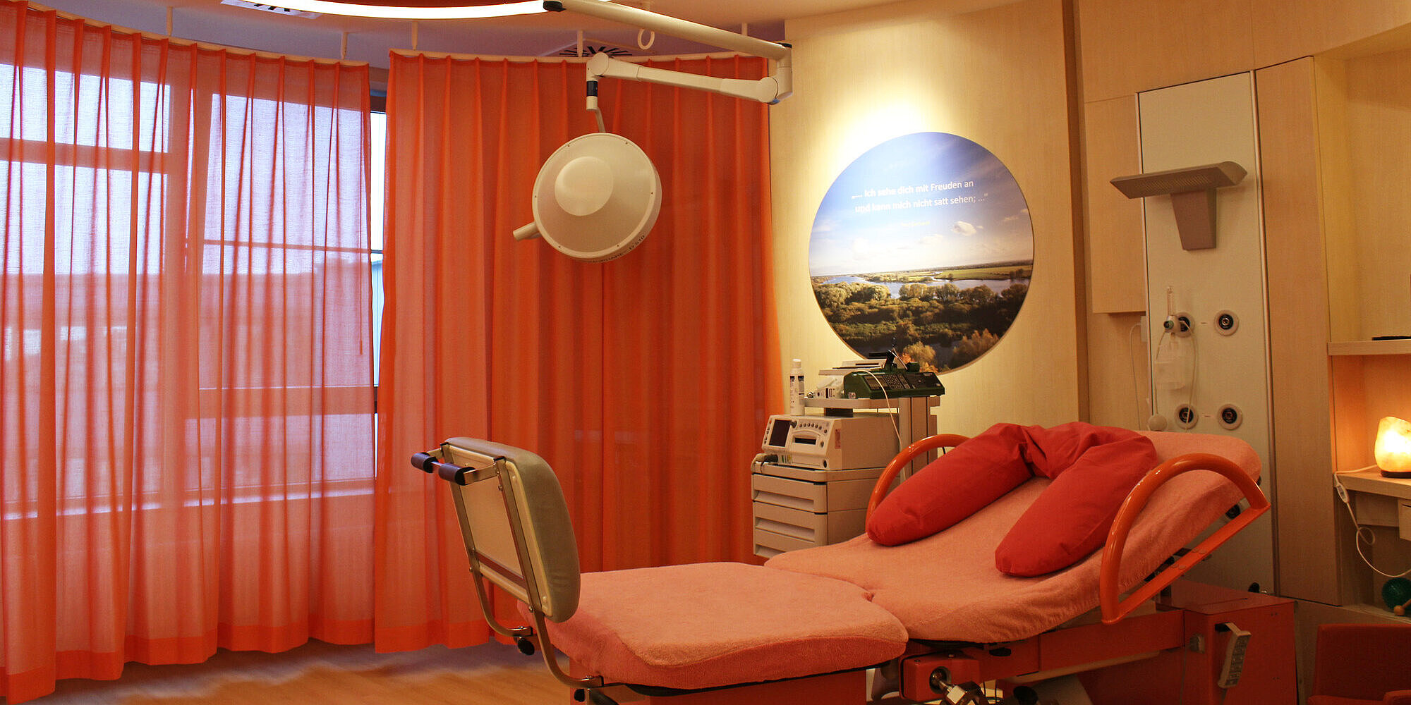 Unsere Kreißsäle bieten größtmögliche Privatsphäre für eine sanfte Geburt Kreißsaal mit Bett und roten Vorhängen