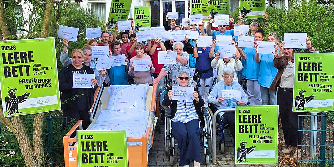 Demo mit Mitarbeitenden der Johannesstift Diakonie, die die Aktion "Das leere Pflegebett" und die Forderung nach einer Überarbeitung des Gesetzesentwurf unterstützt.