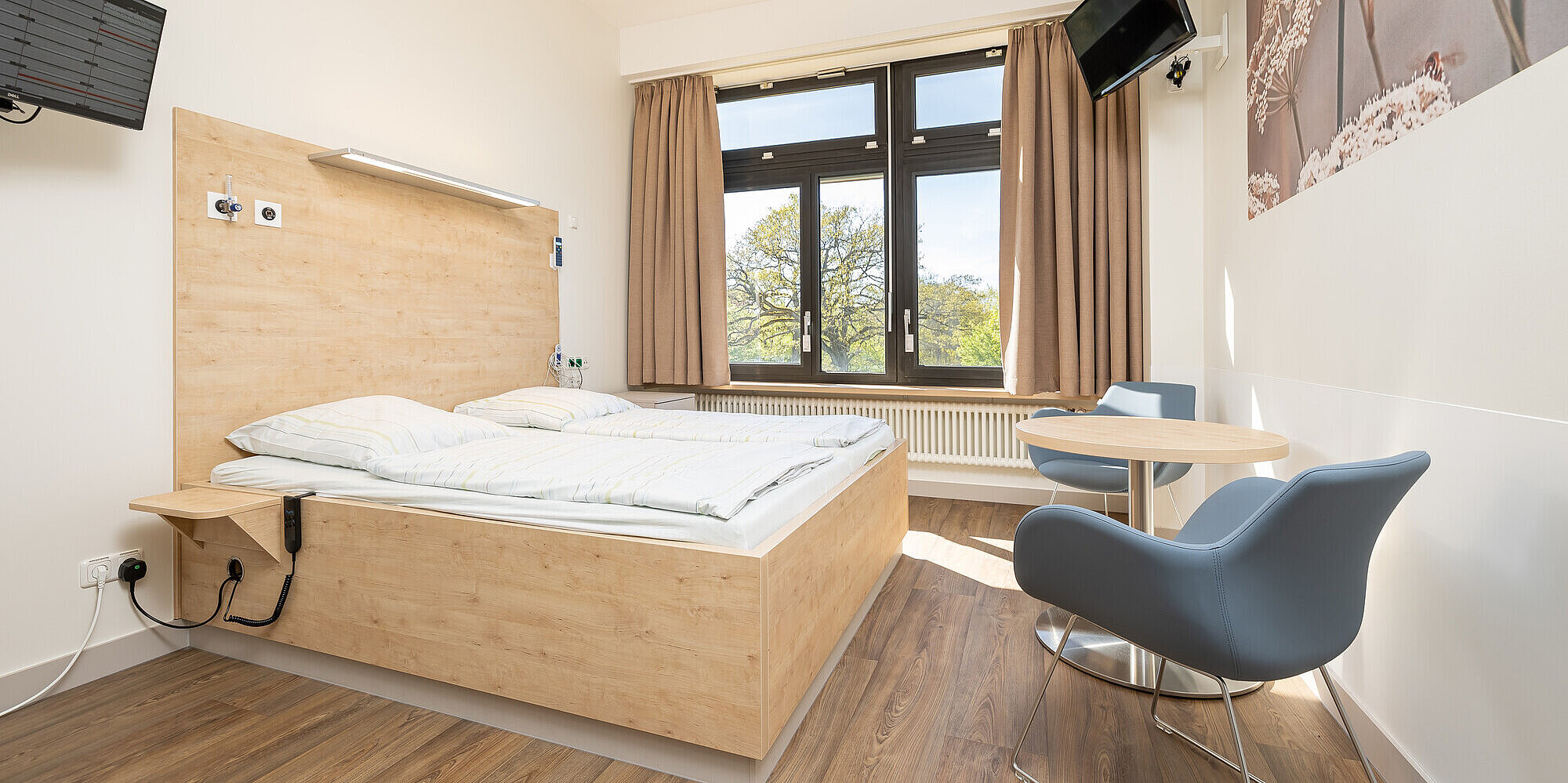 Lichtdurchflutet und modern – unsere Vorwehenzimmer Lichtdurchflutetes Zimmer mit Doppelbett, Tisch und zwei Stühlen.