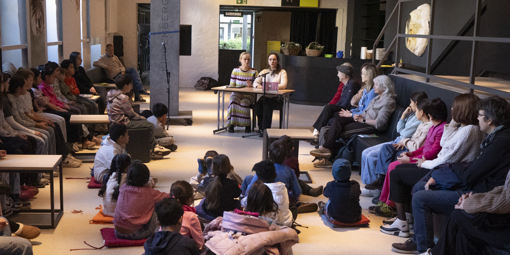 Bundesweiter Vorlesetag im Berliner Ensemble | Foto: Kath Fitz, Berliner Ensemble Viele Kinder in einem Raum, die zwei Vorleserinnen lauschen