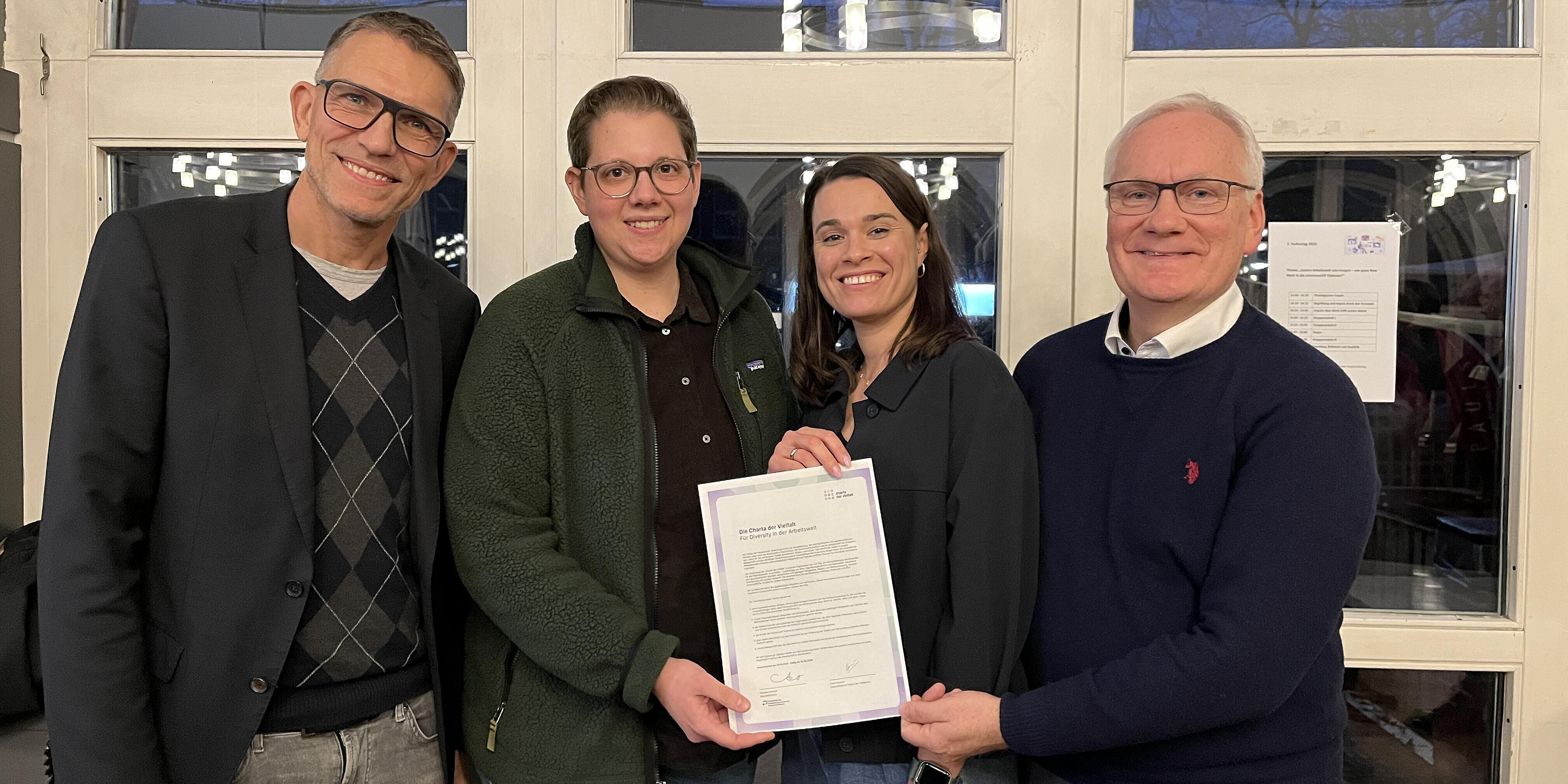 Von links: Geschäftsführer Michael Schmidt, Diversitätsbeauftragte Ingrid Hartog, Referentin Leonie Höfert, Leitender Theologe Dr. Werner Weinholt. Vier Mitarbeitende des Krankenhauses präsentiere die unterzeichnete Urkunde zur Charta der Vielfalt.