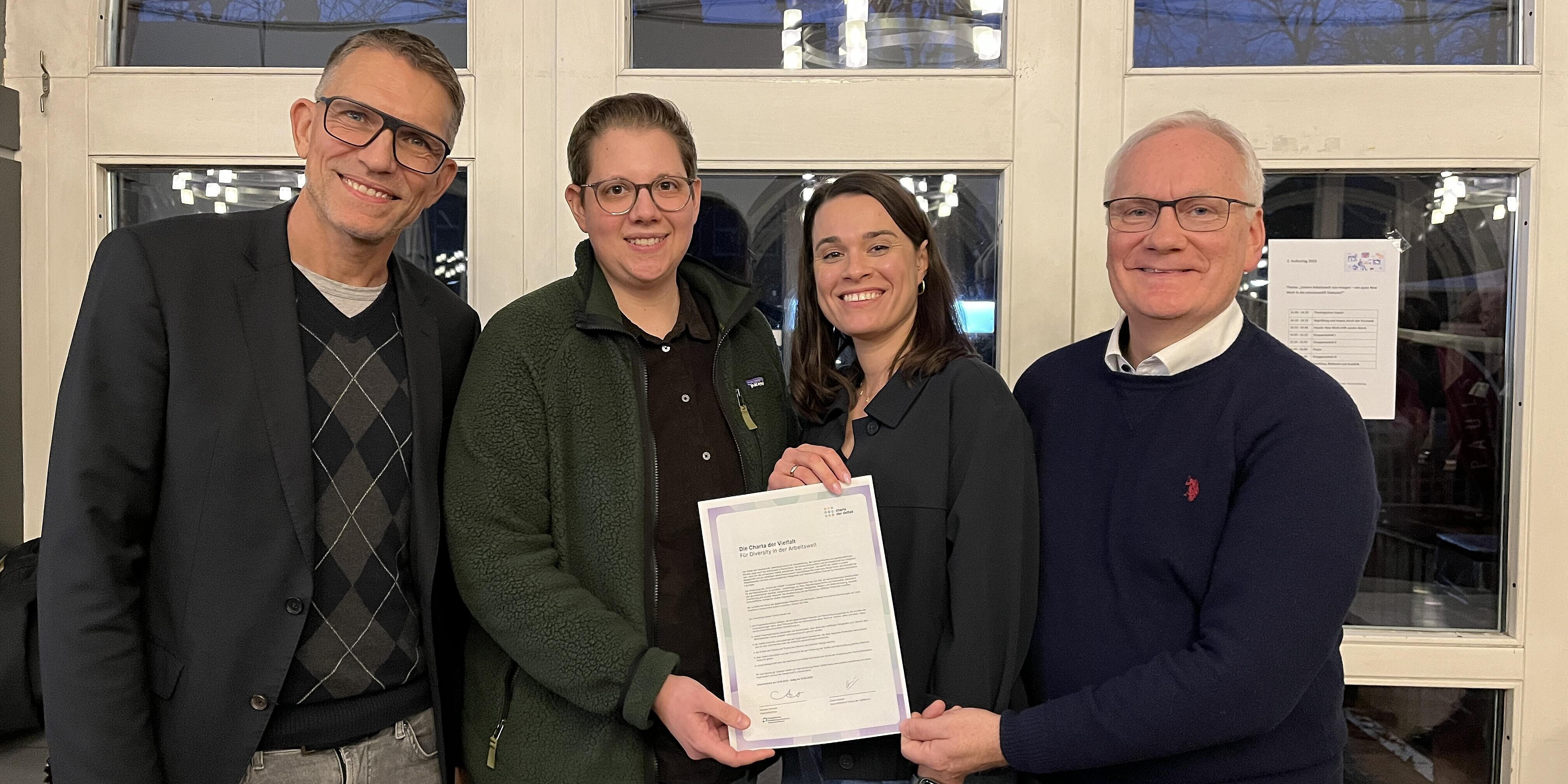 Von links: Geschäftsführer Michael Schmidt, Diversitätsbeauftragte Ingrid Hartog, Referentin Leonie Höfert, Leitender Theologe Dr. Werner Weinholt. Vier Mitarbeitende des Krankenhauses präsentiere die unterzeichnete Urkunde zur Charta der Vielfalt.