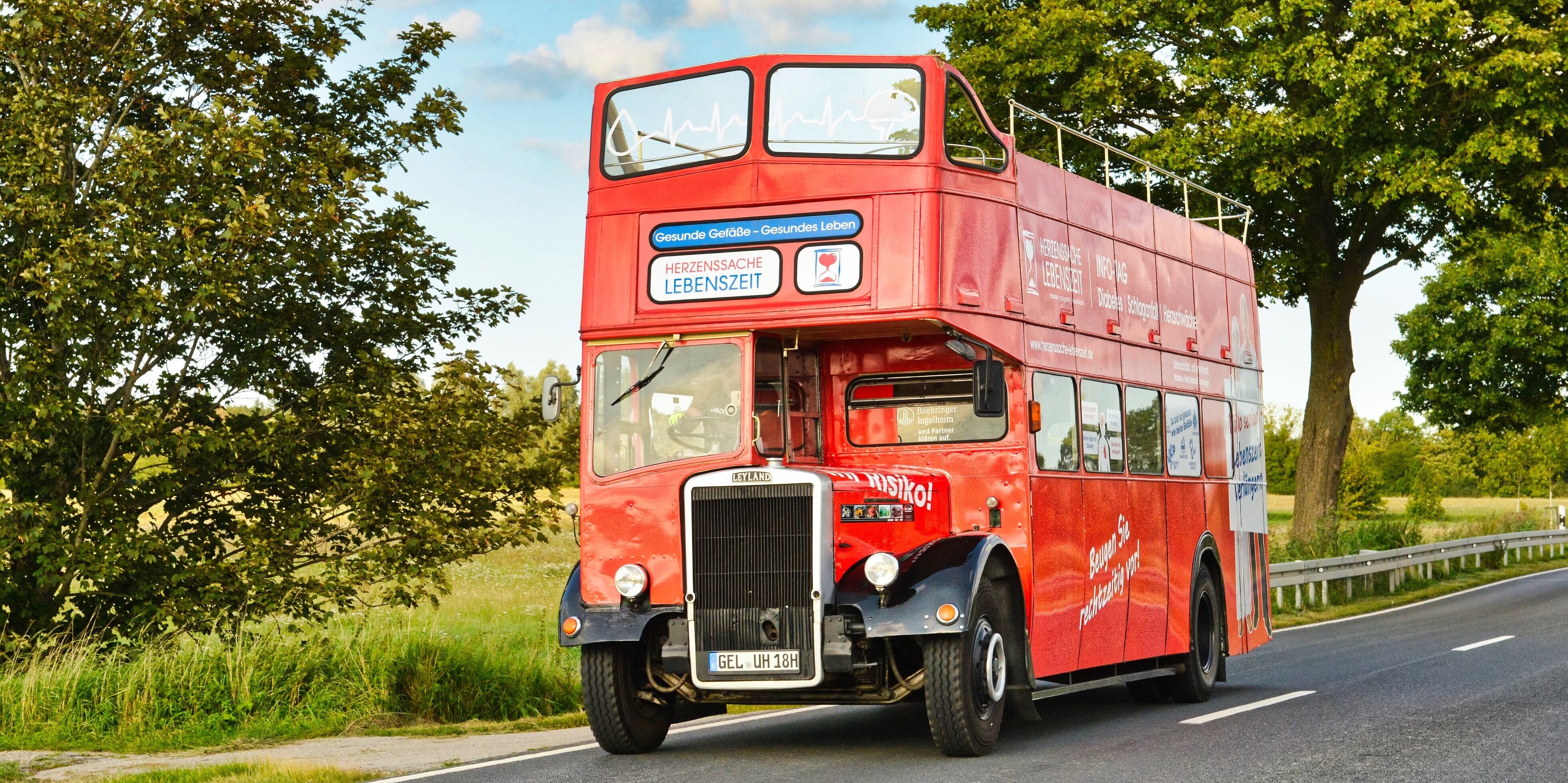 Herzbus kommt nach Coswig: Testen Sie Ihr Risiko für Herzschwäche, Schlafanfall & Diabetes Bild des zweistöckigen roten Oldtimer Buses auf einer Landstraße
